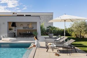 a woman sitting on the edge of a swimming pool at Villa Bewegte Berge in Kaštelir
