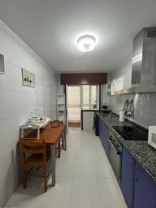 cocina con mesa de madera y armarios azules en Apartamento Xacobe Grove, 120 metros totalmente equipado, luminoso, céntrico y con plaza de garaje, en O Grove