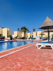 a swimming pool with two lounge chairs and an umbrella at El cortijo Bungalow Playa las Americas in Playa de las Americas