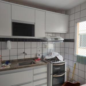 a kitchen with white cabinets and a stove top oven at Apartamento Praia do Morro em Guarapari in Guarapari