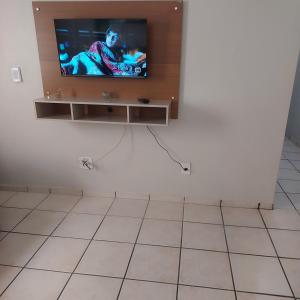 a television on a wall in a room with a tiled floor at Apartamento Praia do Morro em Guarapari in Guarapari