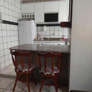 a kitchen with a counter and two chairs at a table at Apartamento Praia do Morro em Guarapari in Guarapari