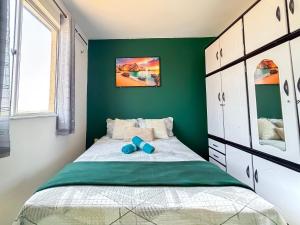 a green bedroom with a bed with blue shoes on it at Apê Bela Vista com Piscina I Wi-Fi e A/C in Imperatriz +31 photos