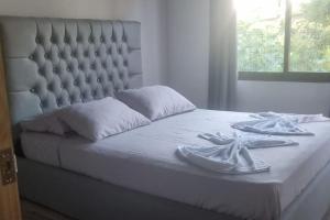 a white bed with two napkins and two dishes on it at Cabinas Guacamaya in Cabuya