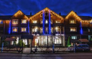 un grande edificio in legno con luci blu di Gotel Milenium a Mykulychyn