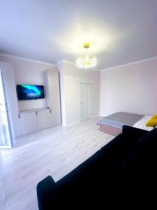 a living room with a bed and a tv at Апартаменты с видом на хан шатыр Центр города in Astana