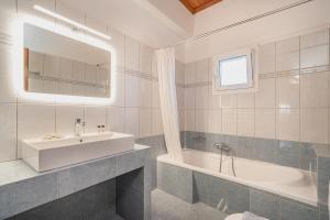 a bathroom with a sink and a tub and a mirror at Kefalonia Horizon Home in Argostoli +86 photos