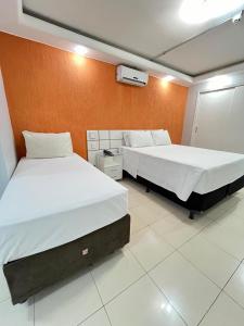 a bedroom with two beds and an orange wall at Flat Centro de Brasília - Garvey Park Hotel 427 in Brasilia