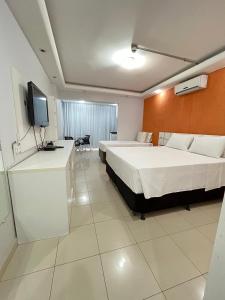 a hotel room with two beds and a flat screen tv at Flat Centro de Brasília - Garvey Park Hotel 427 in Brasilia