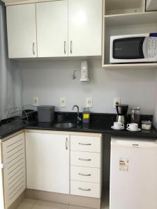 a kitchen with white cabinets and a microwave at Flat Centro de Brasília - Garvey Park Hotel 427 in Brasilia