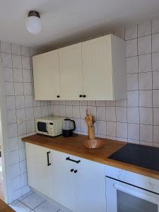 a kitchen with white cabinets and a microwave at Beachbungalow in Karlshagen