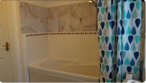 a bathroom with a tub and a shower curtain at Family Friendly Room in Manchester