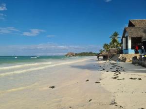 a beach with footprints in the sand and a building at Villa Ark Zanzibar in Paje +4 photos