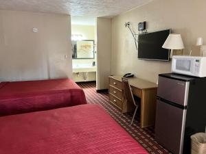 a hotel room with two beds and a desk with a microwave at Economy Inn McCook in McCook