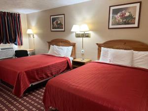 a hotel room with two beds with red sheets at Economy Inn McCook in McCook