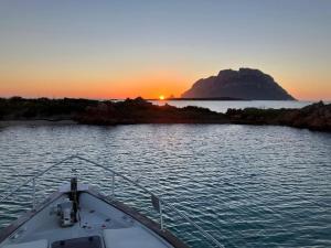 a boat in a body of water with the sunset at Sleeping on a boat in the Island's bay in Porto San Paolo