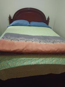 a bed with a wooden headboard and blue pillows on it at Albergue Camry Backpackers佳美背包客旅馆 in Cuenca
