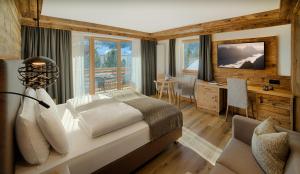 une chambre avec un lit, un bureau et une télévision dans l'établissement Hotel Villa Eden, à Corvara in Badia