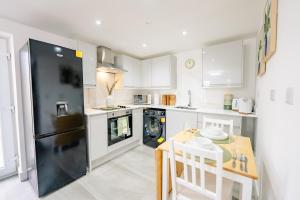 a kitchen with a black refrigerator and a table at Amias Homes in Cardiff