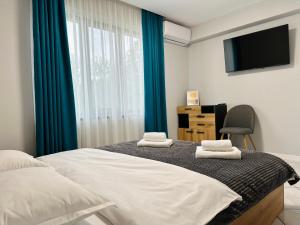 a bedroom with a bed with blue curtains and a television at Къща за гости ЕМ Парадайс 2 in Tserova Koriya +38 photos