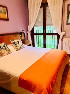 a bedroom with a bed with an orange blanket and a window at Senda de las mariposas Vinuesa in Vinuesa