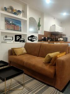 a brown couch in a living room with a kitchen at Le Petit Cocon - Parking privé - Lyon Sud in Vénissieux