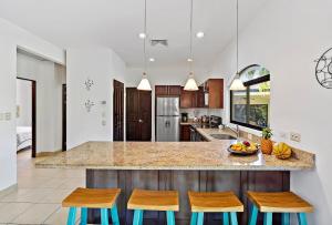a kitchen with a island with two chairs and a counter at Garden Pool & 5-minutes Walk to Beach in Potrero +9 photos