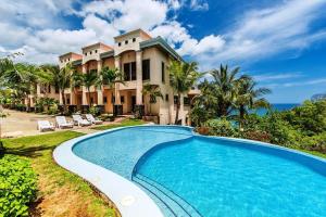a villa with a swimming pool in front of a house at Oceanfront Infinity Pool and Sunset Veranda in Playa Flamingo