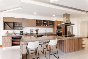 a kitchen with a large island with bar stools at Langosta Beach Ocean View Penthouse w Pool in Tamarindo