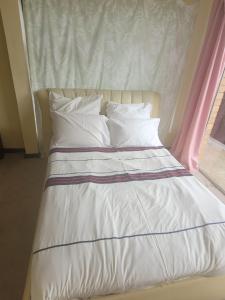 Una cama con sábanas y almohadas blancas y una ventana. en 44 on Lyme Road, en St Francis Bay