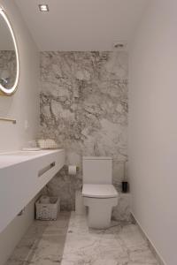 Un baño con inodoro blanco y pared de mármol. en Antic Rooms Varadero, en Villajoyosa