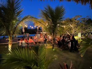 a group of people sitting at tables near a pool at night at LaVentana Tatajuba in Tatajuba