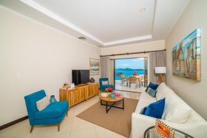 a living room with a white couch and blue chairs at Oceanviews, Private Veranda, 2 Pools & Concierge in Playa Flamingo