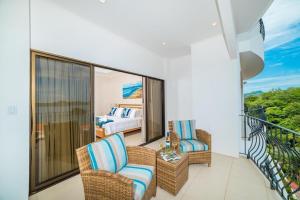 a room with a balcony with a bed and chairs at Oceanviews, Private Veranda, 2 Pools & Concierge in Playa Flamingo +13 photos
