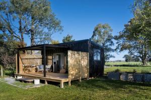 a black tiny house with a porch in a field at One77 Rural Retreat in Matarawa
