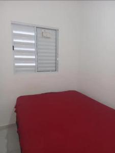 a bedroom with a red bed and a window at casa itanhaém in Itanhaém