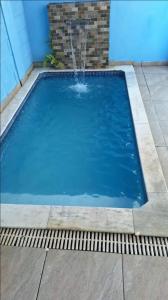 a large blue swimming pool with a fountain at casa itanhaém in Itanhaém +8 photos