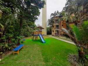 a playground in a yard next to a building at Riviera de São Lourenço Apto Completo com Churrasqueira Serviço de Praia Piscina aquecida Sauna salão de jogos e quadra in Riviera de São Lourenço