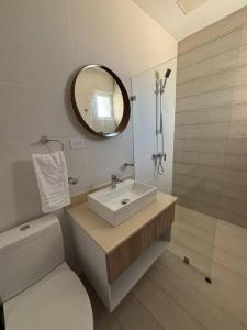 a bathroom with a sink and a mirror and a toilet at Corals Retreat 2BR Beach Condo in Punta Cana