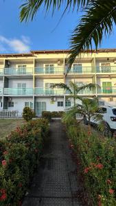 a large building with a palm tree in front of it at Flats Duplex Super Aconchegantes e Confortáveis in Maragogi