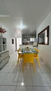a kitchen and dining room with a table and yellow chairs at Flats Duplex Super Aconchegantes e Confortáveis in Maragogi