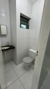 a white bathroom with a toilet and a window at Flats Duplex Super Aconchegantes e Confortáveis in Maragogi +39 photos