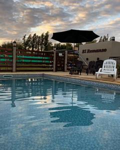 a swimming pool with two chairs and an umbrella at El Remanso in San José