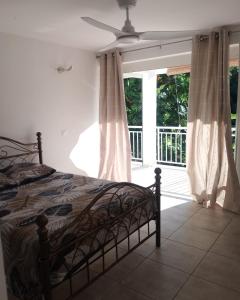 a bedroom with a bed and a window with curtains at Le Triton in Deshaies