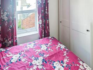 ein Bett mit einer rosa Bettdecke und einem Fenster in der Unterkunft Kathali Cottage in Exmouth