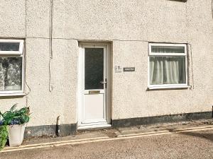 ein Haus mit einer weißen Tür und zwei Fenstern in der Unterkunft Kathali Cottage in Exmouth