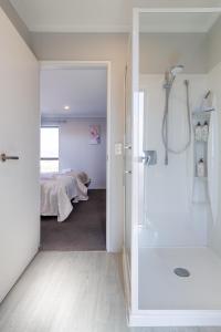 une salle de bain avec douche et une chambre avec un lit dans l'établissement Wigram Escape Minutes to Ngā Puna Wai Sports Hub, à Christchurch