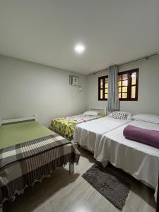 a bedroom with two beds and two windows at Granja Raio de Luz in Igarassu +25 photos