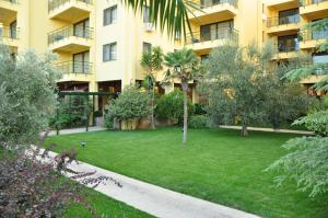 a large apartment building with a yard with trees at Palm Court Suites in Ayvalık
