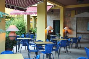 an empty patio with tables and blue chairs at Palm Court Suites in Ayvalık